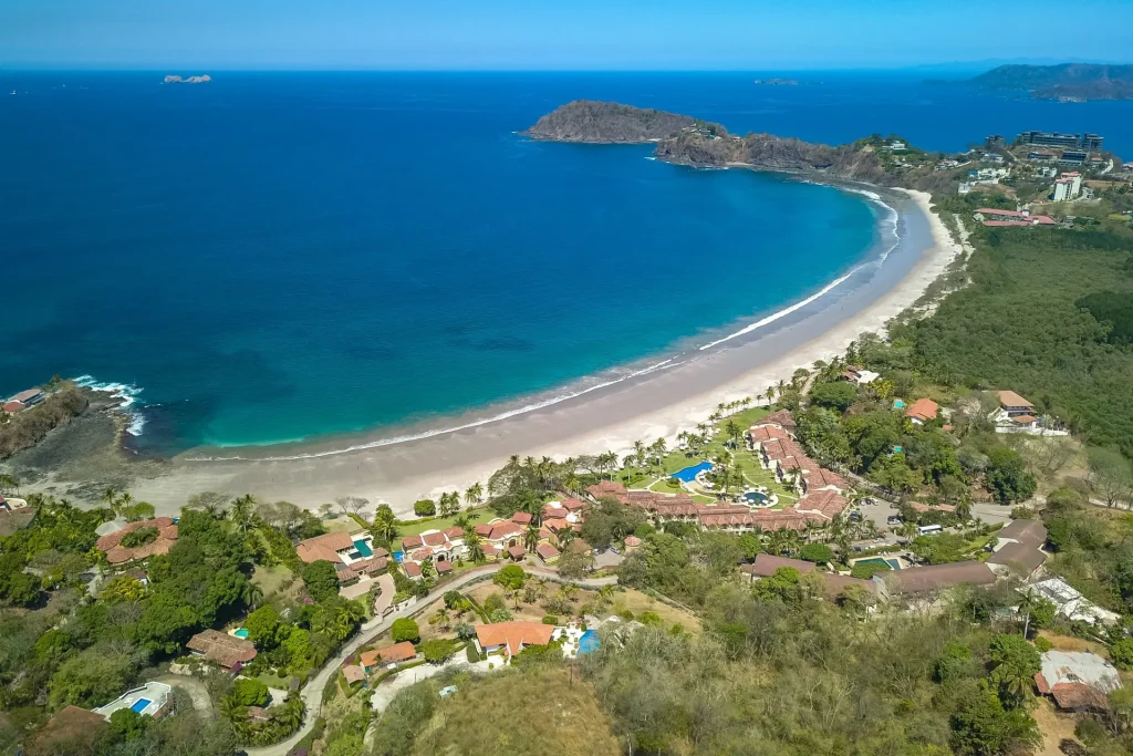 Aerial view of Playa Flamingo, Costa Rica, with its curved white-sand beach and homes along the shore