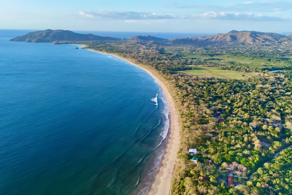 Aerial view of Playa Grande’s long surf beach, with the town, forest and hills of Guanacaste, Costa Rica
