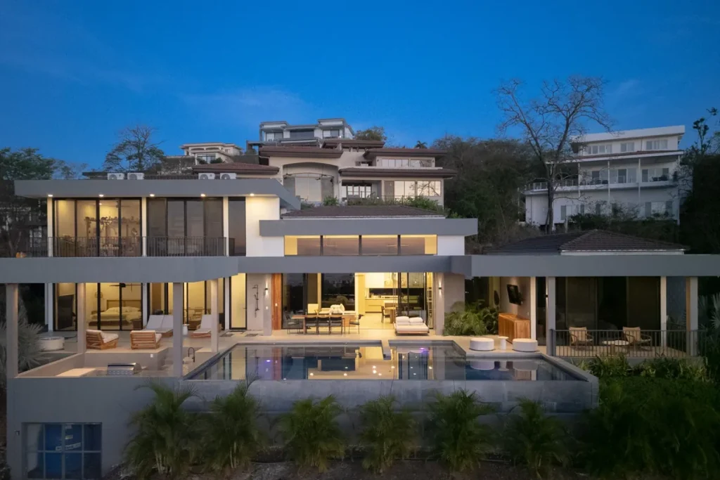 Modern hillside home with a pool and covered terraces at dusk in Playas del Coco