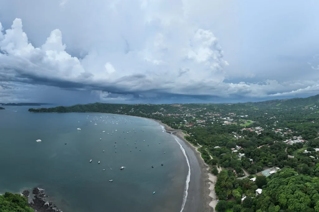 Aerial view of Playas del Coco's bay, beach and town, with boats at anchor and green hills behind, Guanacaste, Costa Rica