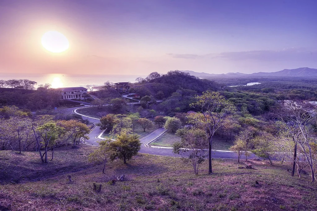 Sunset over the ocean from the Senderos hillside, with winding community roads below, Tamarindo, Costa Rica